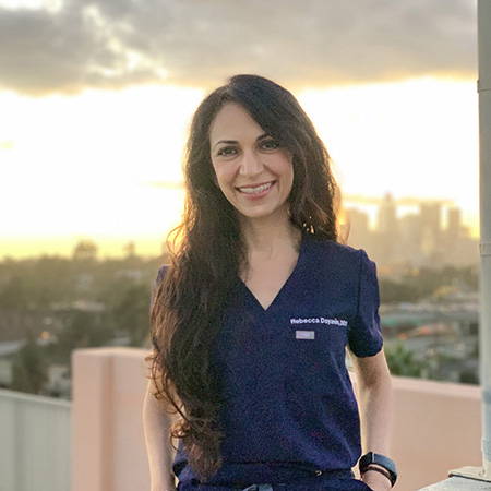 Rebecca dayanım in scrubs with city of Los Angeles behind her