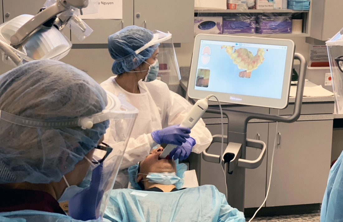Dental students watching an endodontist use a new intramural scanner on a patient.