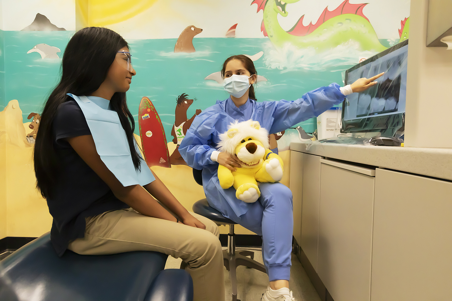 Dental resident showing pediatric dental patient their charts on a computer screen
